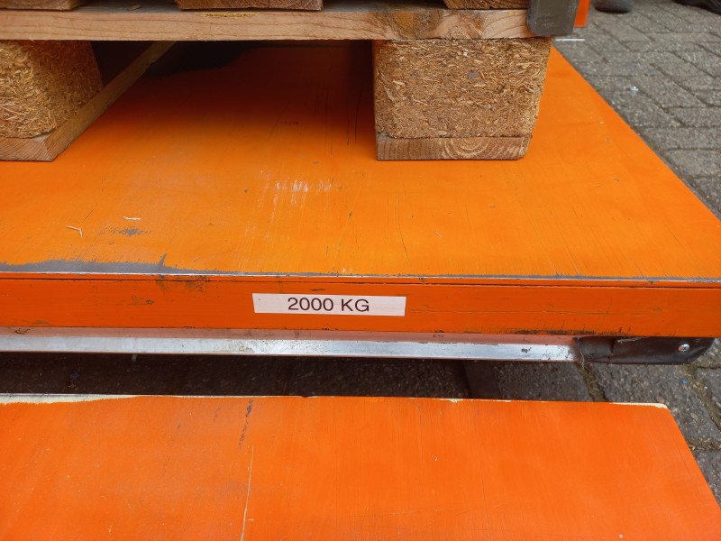 Gebruikte elektrische schaarheftafel met oprijplateau en draagvermogen van 2000 kg. Stalen heftafel met hydraulische cilinder, handbediening, noodstop en hefbereik van 80 tot 850 mm.